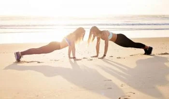 Two Women Planking At The Seashore